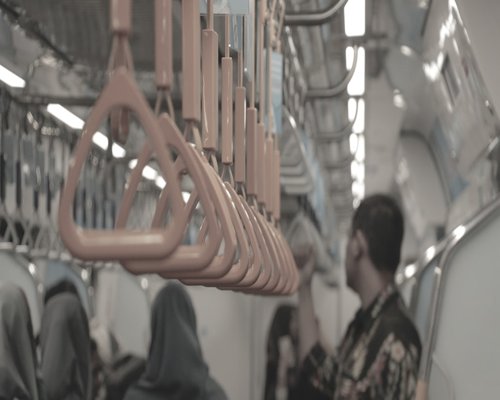 Interior of an Indonesian commuter train with passengers holding handrails