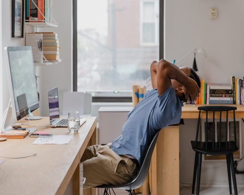 Individual stretching arms over head while sitting at a desk